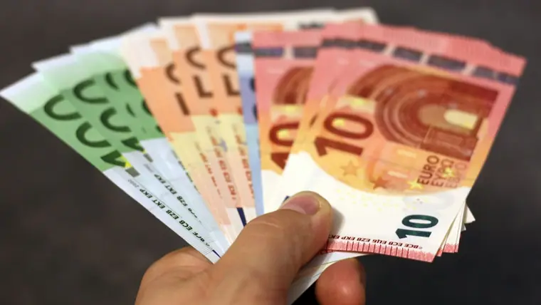 Schadenersatz: Hand hält aufgefächerte Euro-Banknoten