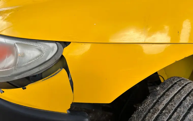 Bagatellschaden: verschobene Stoßstange am Scheinwerfer eines gelben Autos
