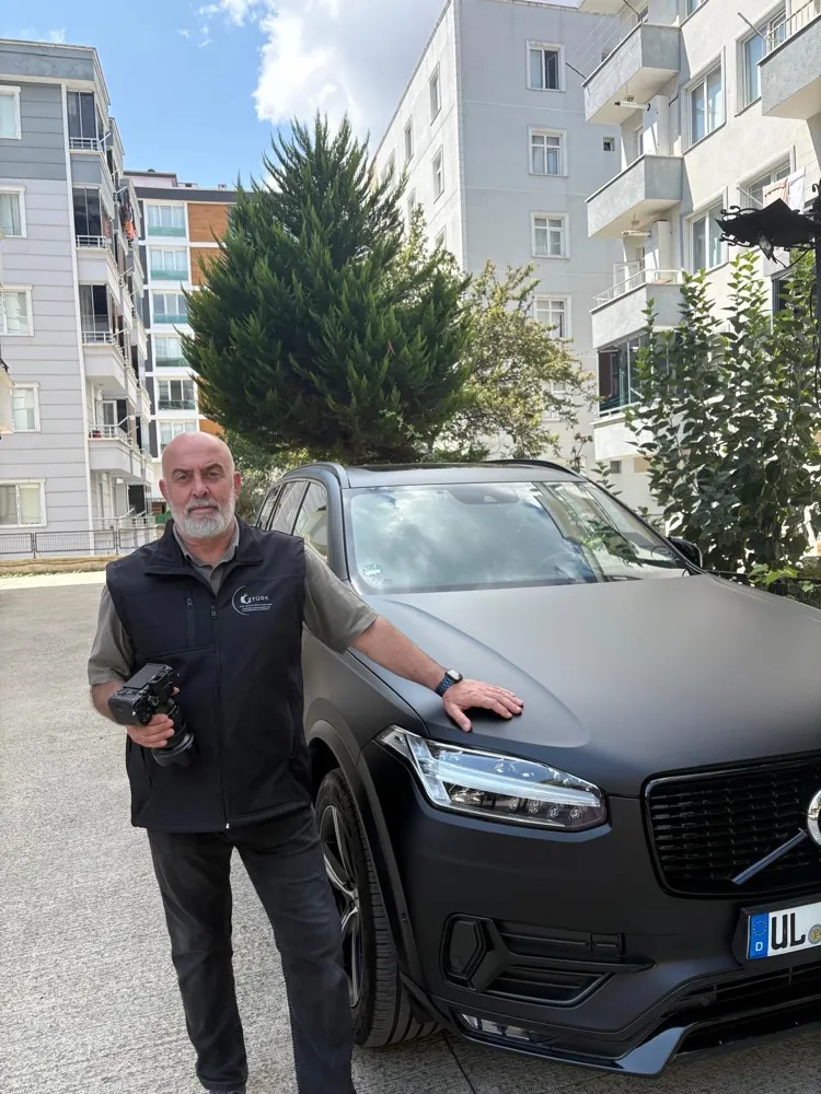 Kfz-Gutachter Abdülkerim Öztürk mit Kamera neben einem Fahrzeug in Ulm